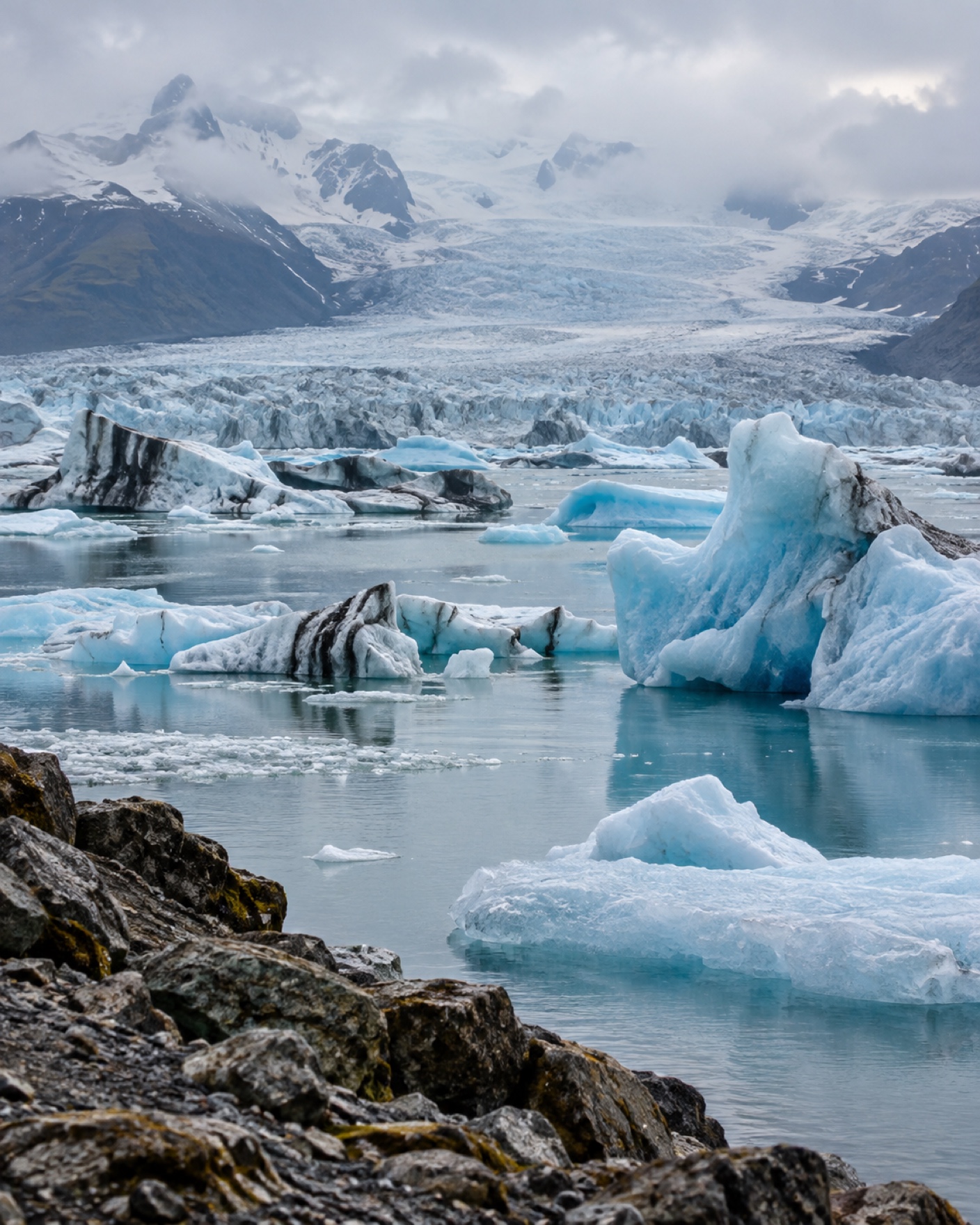 Wide view across Jökulsárlón glacier lagoon with blue icebergs drifting beneath the Vatnajökull ice cap